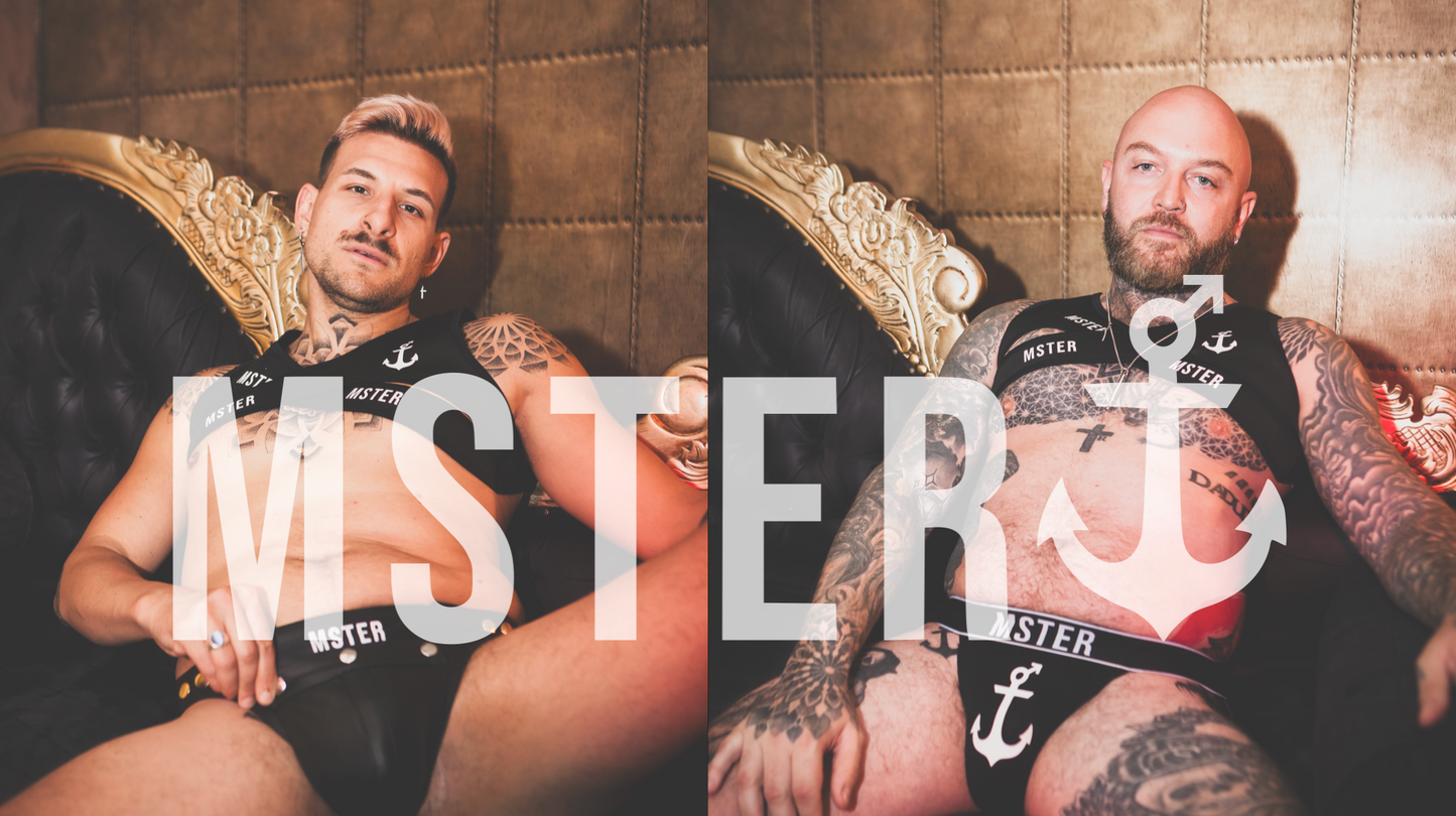 Men in MSTER branded underwear and chest harness, posing on ornate chair, showcasing tattooed physique