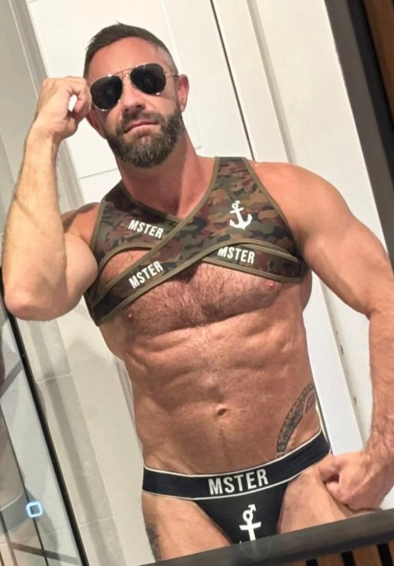 Man wearing a camouflage Fetish Harness and black underwear with 'MSTER' branding.
