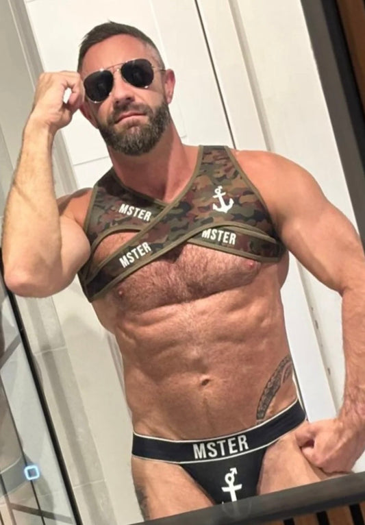 Man wearing a camouflage Fetish Harness and black underwear with 'MSTER' branding.
